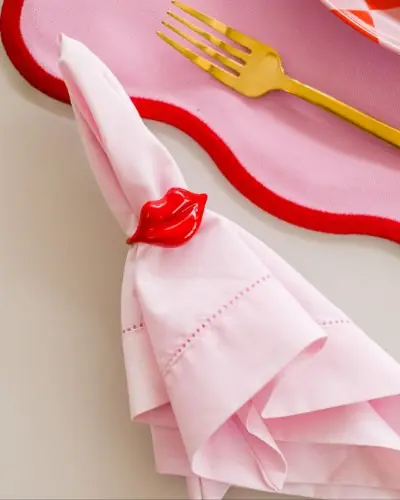 Guardanapo rosa com porta-guardanapo vermelho em forma de boca